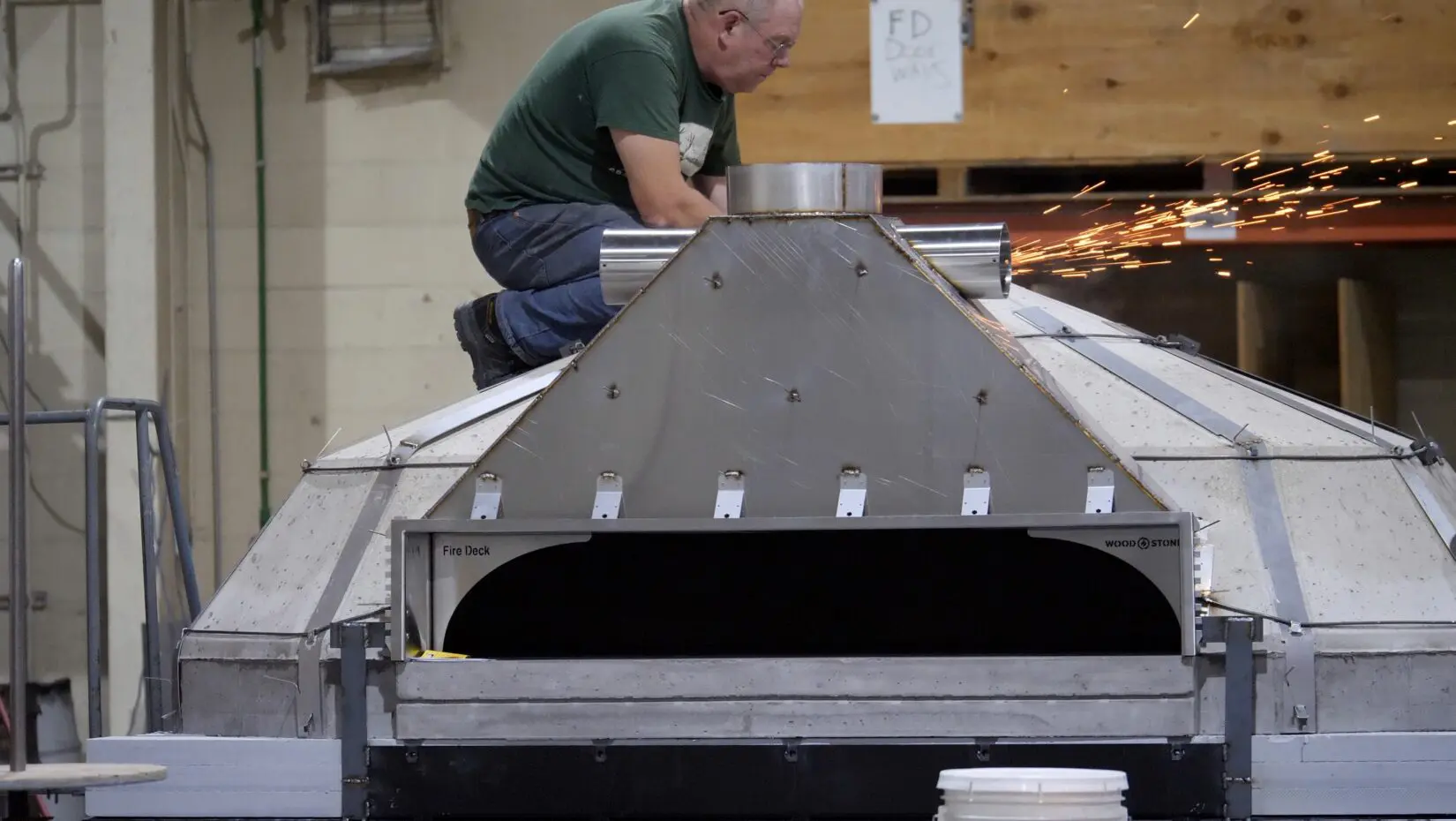 A worker on top of a Fire Deck Stone Hearth Oven.