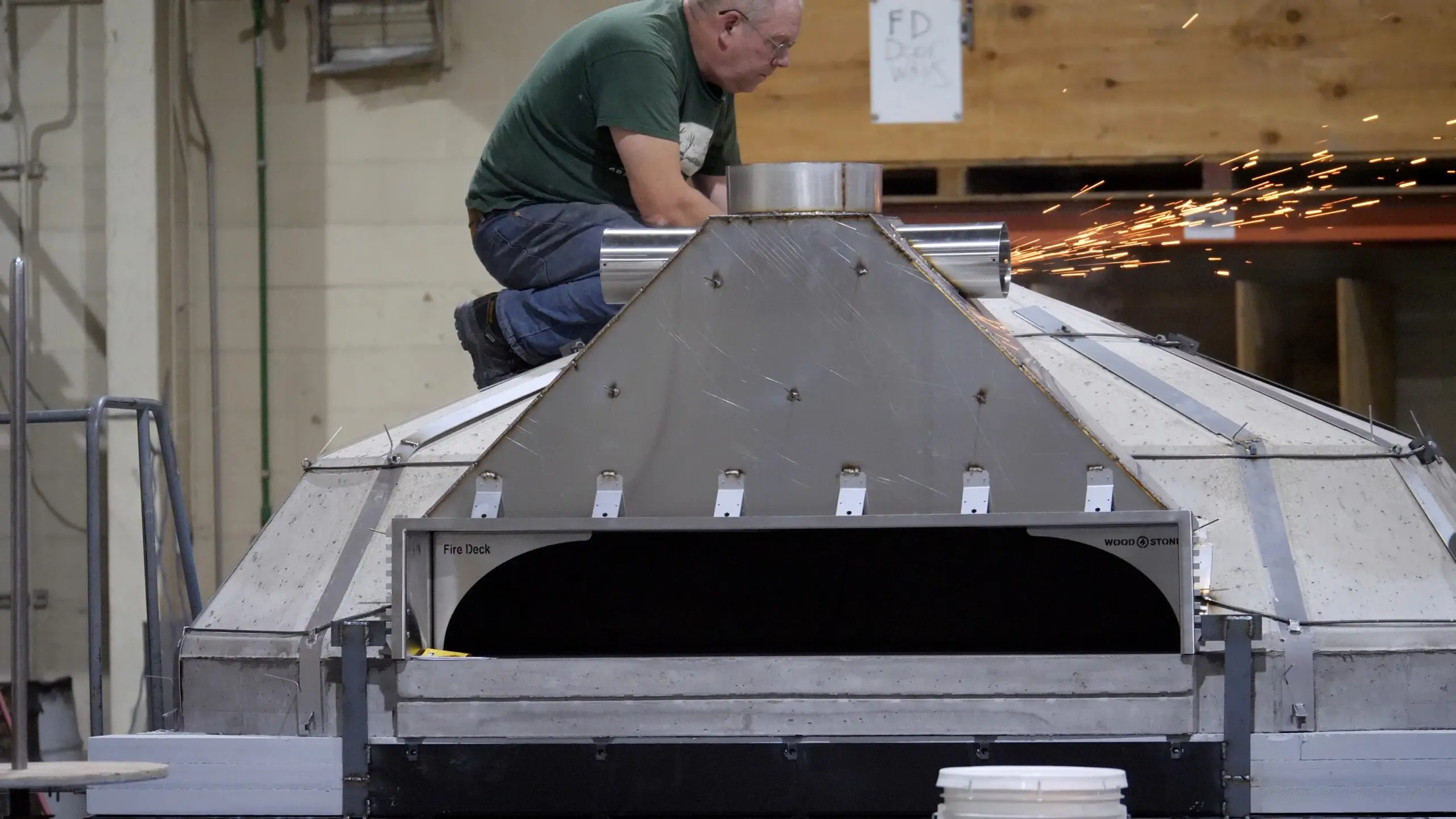 A worker on top of a Fire Deck Stone Hearth Oven.