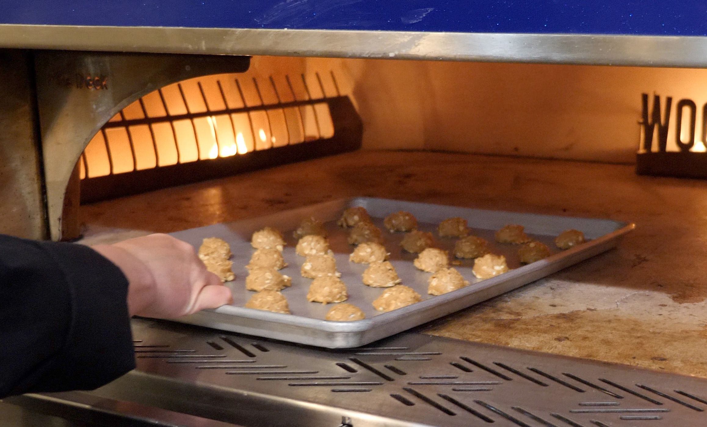 Chef loading cookies to bake in a Wood Stone Fire Deck oven